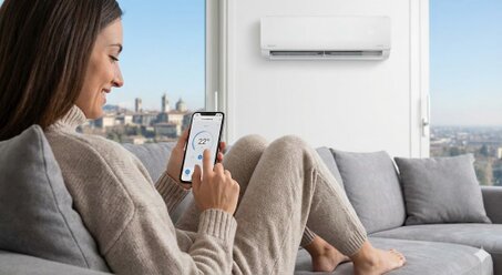 Uomo controlla condizionatore wifi con smartphone in appartamento a Bergamo